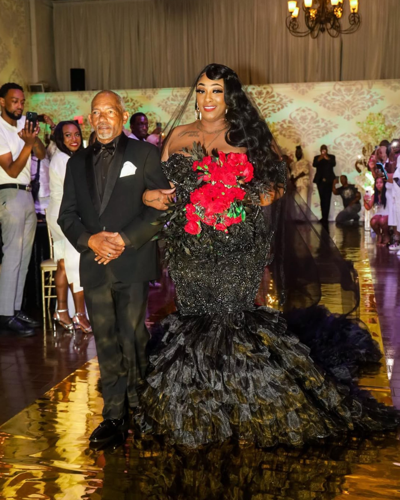 Woman in a black gown with red flowers at a formal event