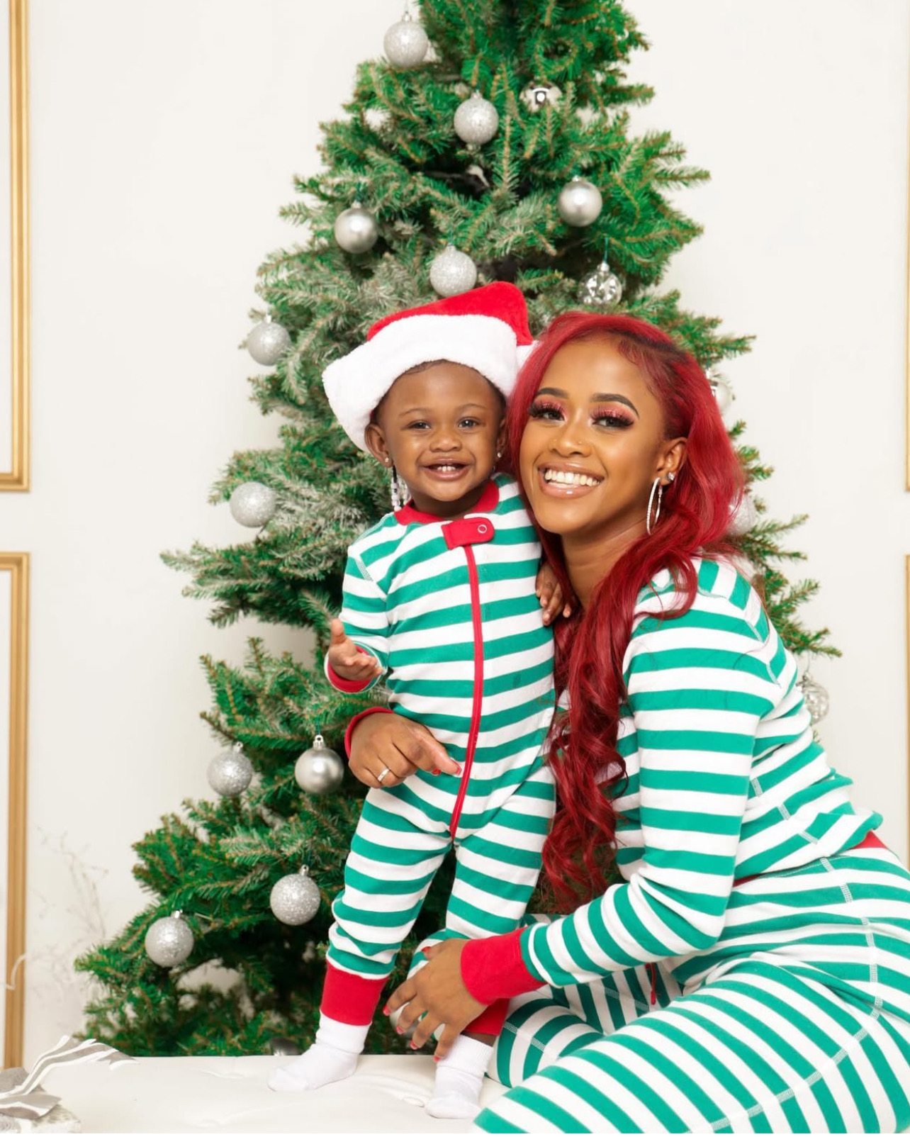 Woman and child in matching striped holiday outfits by a Christmas tree