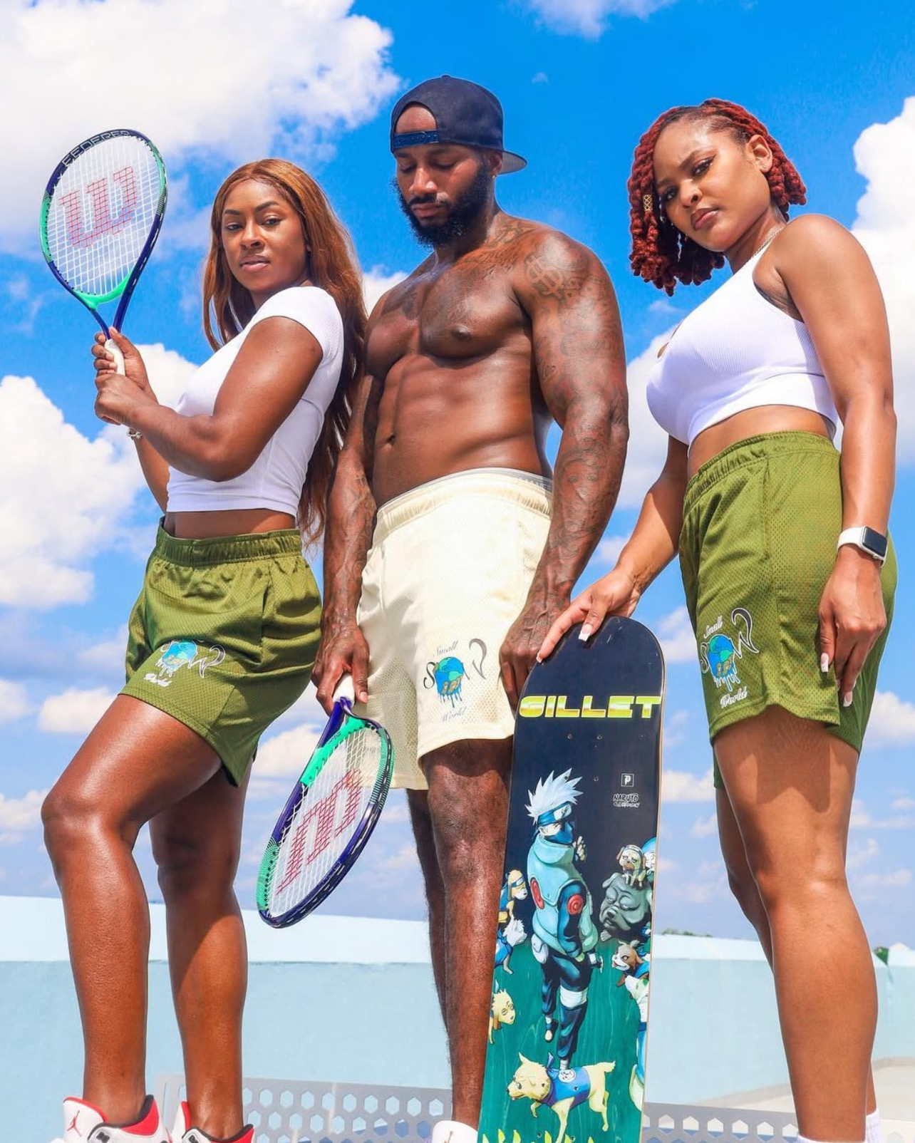 Three people posing with tennis rackets under a blue sky